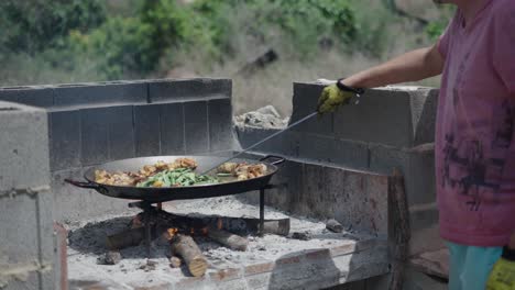 preparing paella outdoors over a wood fire