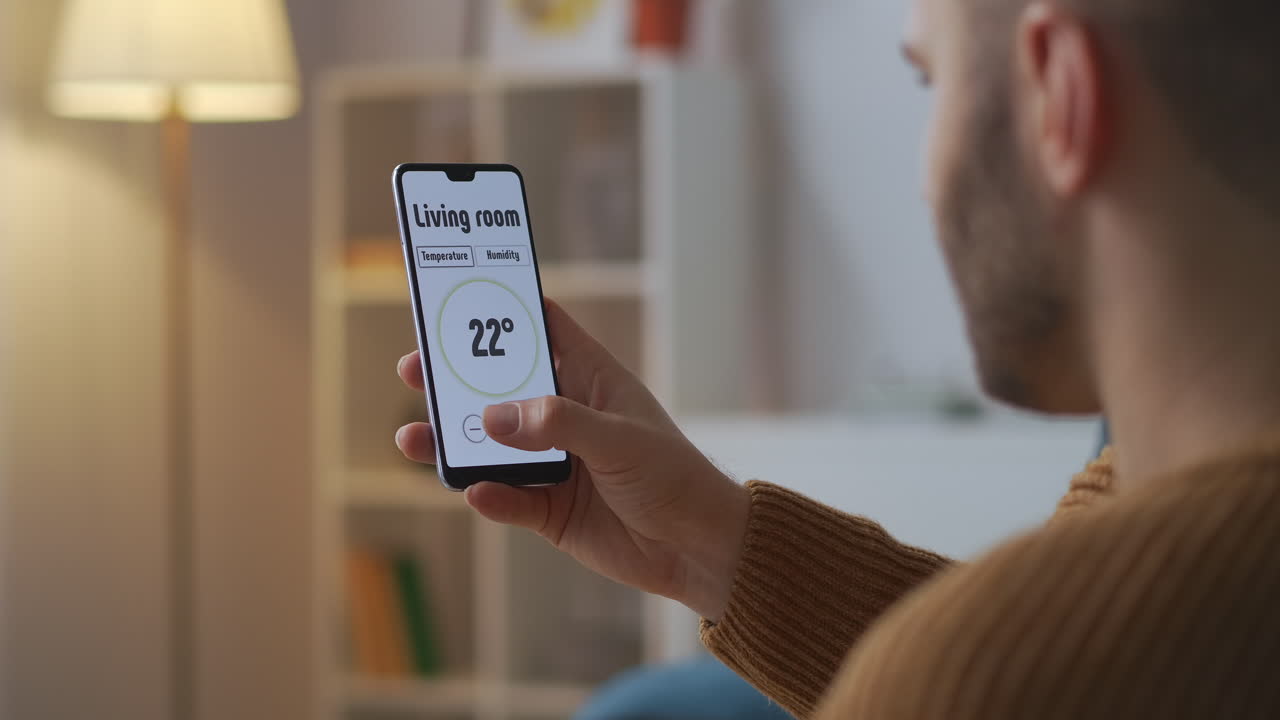 la tecnología del hogar inteligente el hombre está controlando por aplicación en el teléfono inteligente ajustando la temperatura en las habitaciones vista de primer plano de la pantalla en las manos