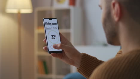 smart-home-technology-man-is-controlling-by-application-in-smartphone-adjusting-temperature-in-rooms-closeup-view-of-display-in-hands
