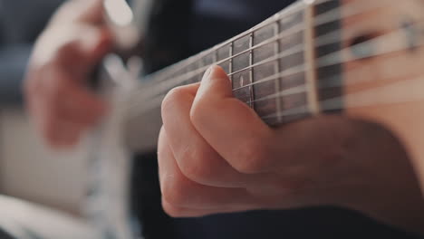 the hands of an unrecognizable man playing chords on a ukulele