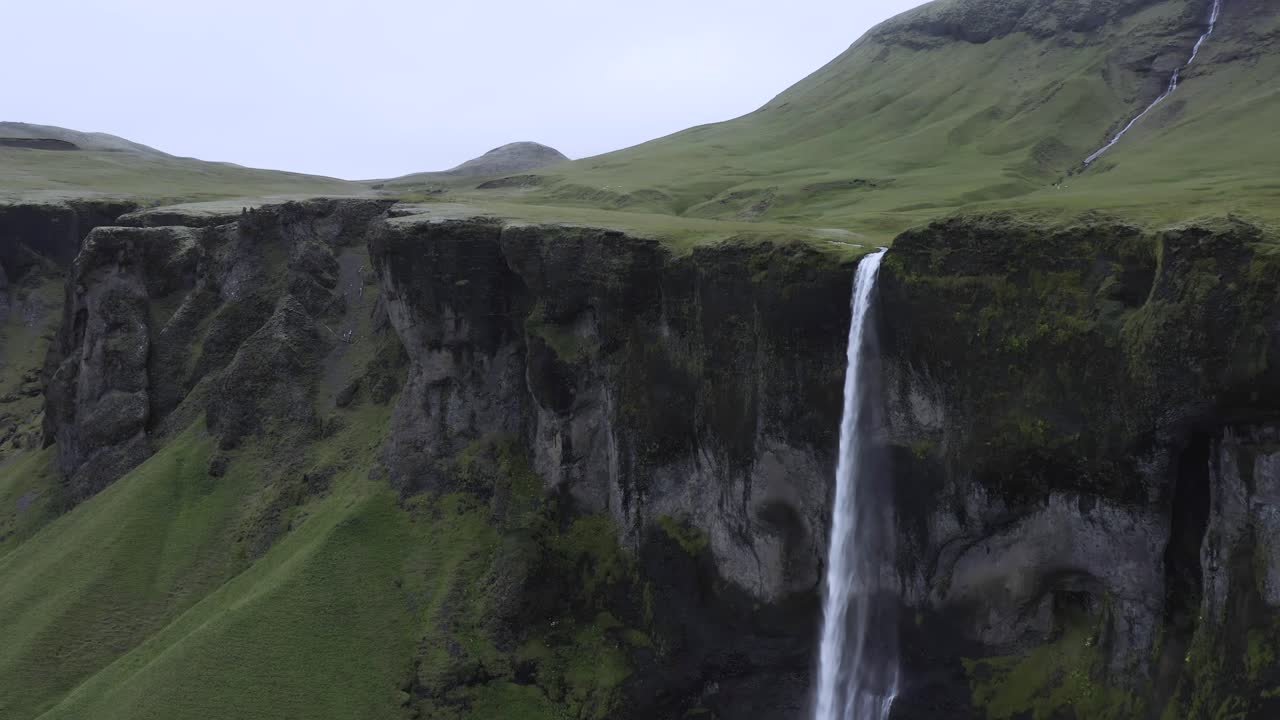 poderosa cascada fluye desde un acantilado en islandia durante el día nublado, antena