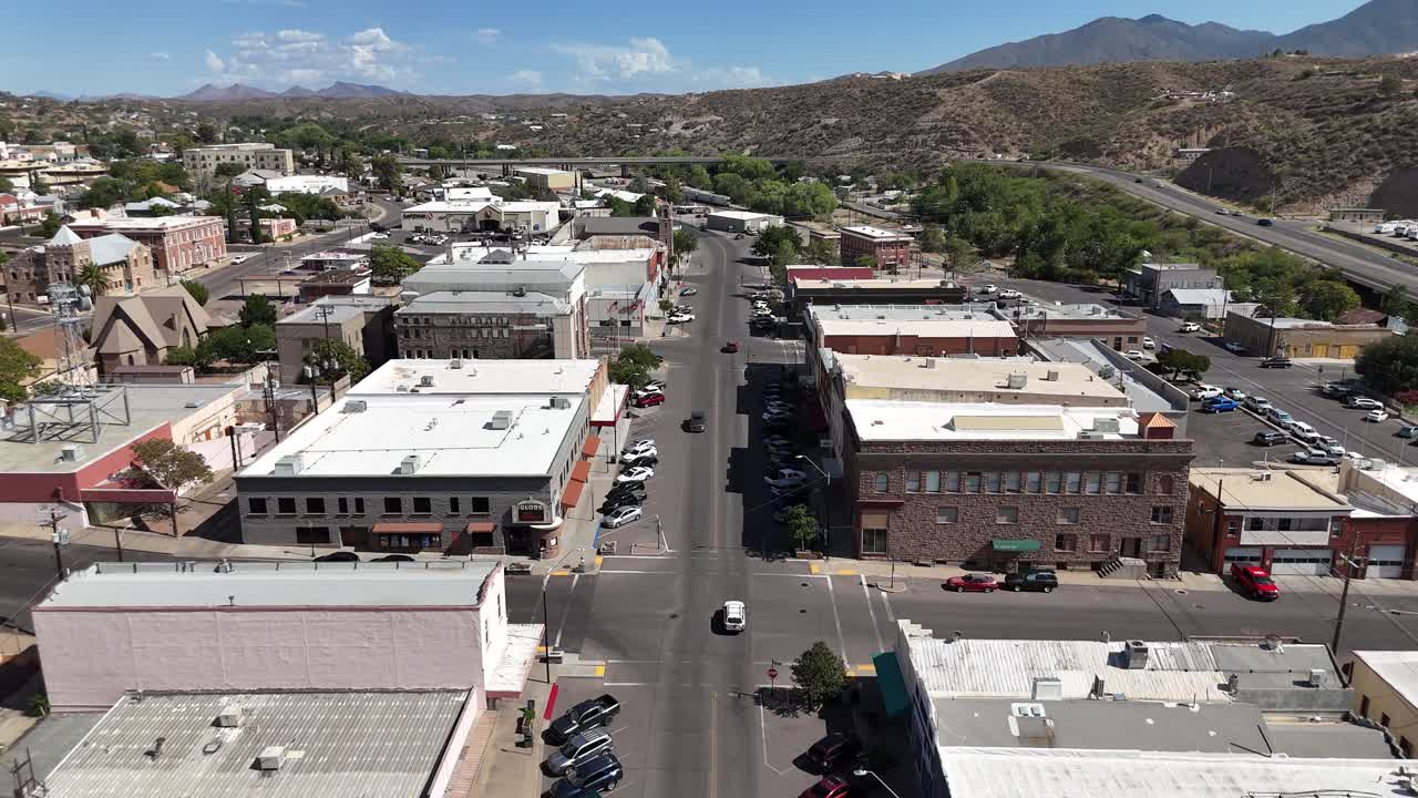 Drone Flying over Downtown Globe Arizona from North to South Broad Street, Mountains in background partly cloudy, cars parked on side of street
