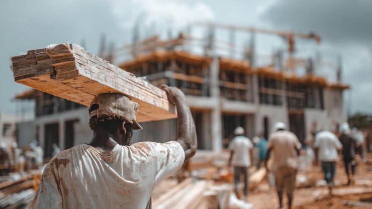 Een ervaren arbeider manoeuvreert hout op een bouwplaats met een gebouw in aanbouw, waarmee het werk en de toewijding van arbeiders in de stedelijke ontwikkeling worden getoond