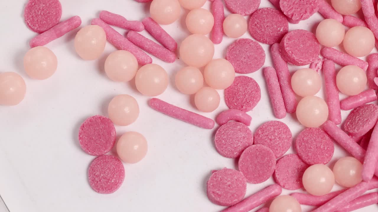 Close-up video of pink candies rotating, showcasing various shapes and textures under bright lighting