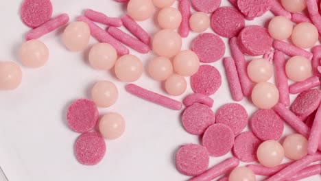 close-up video of pink candies rotating, showcasing various shapes and textures under bright lighting