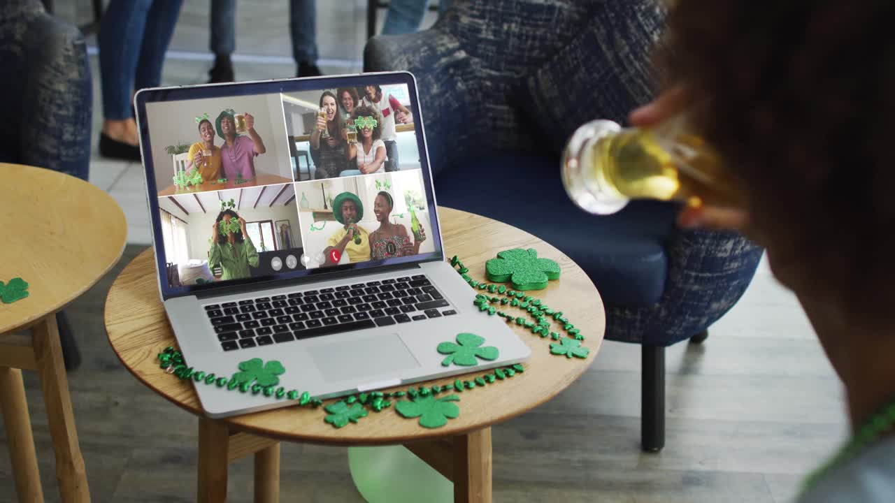 Person at bar using laptop making st patrick's day video call with friends at another bar