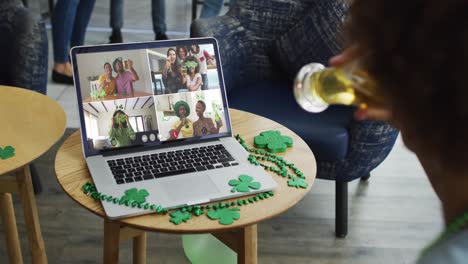 persona en un bar usando una computadora portátil haciendo una videollamada del día de san patricio con amigos en otro bar