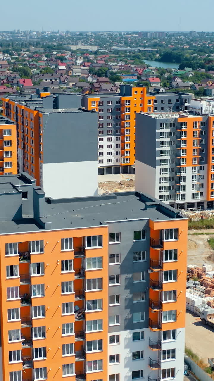 New city complex. Tall urban apartment buildings with colorful walls. Residential area with newly built multi-storey houses. Aerial view. Vertical video
