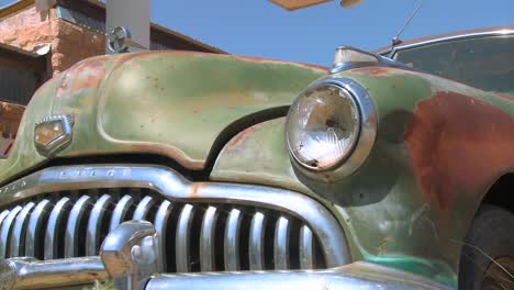 A-slow-moving-shot-tracking-along-an-old-rusted-car-at-an-abandoned-trading-post-2