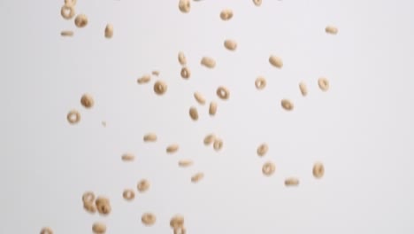 cheerios cereal raining down on white backdrop in slow motion