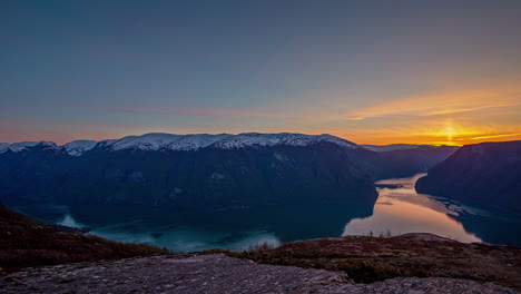 Schneebedeckte-Berge,-Die-Während-Eines-Farbenprächtigen-Sonnenuntergangs-Weit-Unten-In-Das-Wasser-Des-Fjords-Eintauchen---Zeitraffer