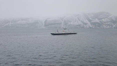 drone shot orbiting a small ferry boat sailing on the coast of norway
