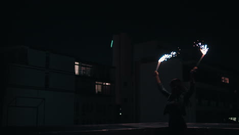 happy-young-woman-holding-sparklers-dancing-on-rooftop-at-night-celebrating-new-years-eve-enjoying-holiday-celebration