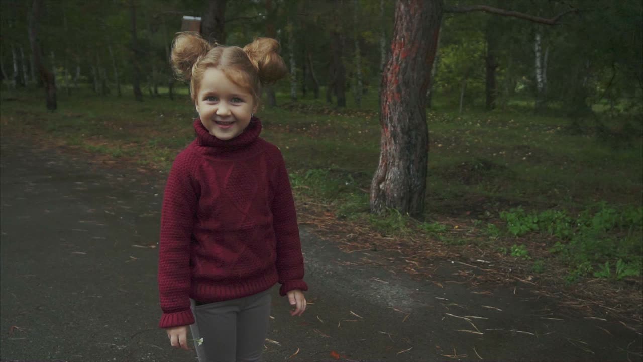 Tyttö punaisessa neuleessa puistossa sateisena päivänä