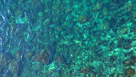 transparent turquoise water flows between rocks in a bay in ibiza, spain. spectacular aerial view flight vertical bird's eye view ascending drone