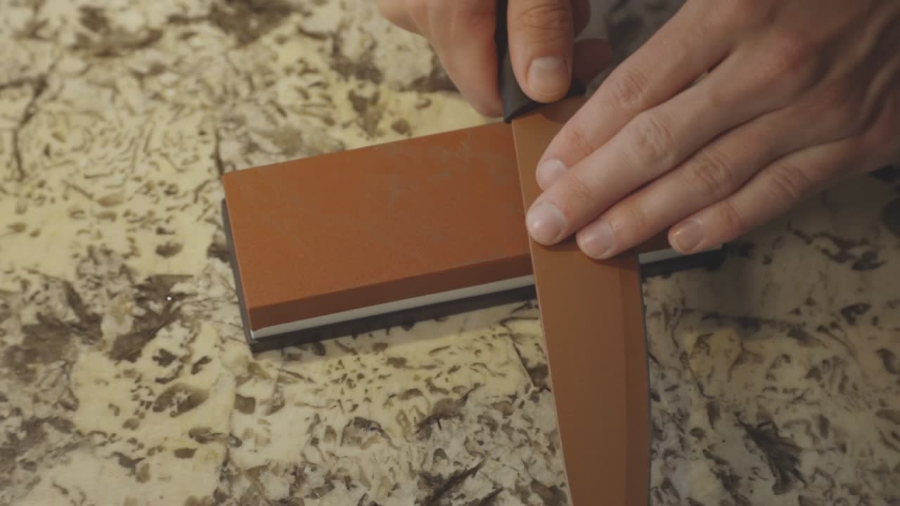 persona afilando el cuchillo en la piedra afilada. - primer plano