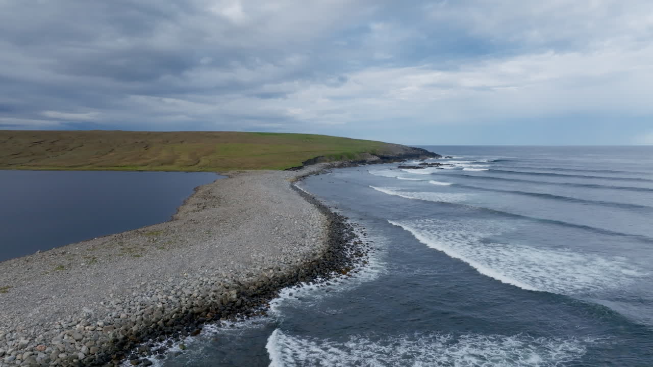 Droneoptagelse af Isle of Lewis, der viser tydelige atlantiske bølgelinjer, som ruller ind i bugten ved siden af stenstranden, der adskiller Loch Mor Bharabhais fra havet. Dramatisk hebridisk kystlinje
