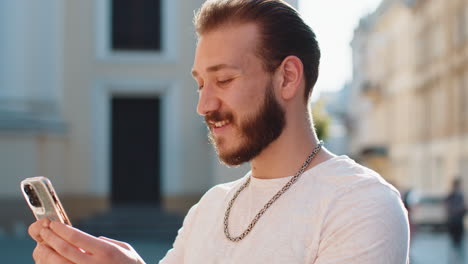 young man use smartphone typing text messages browsing internet finishing work looking at camera
