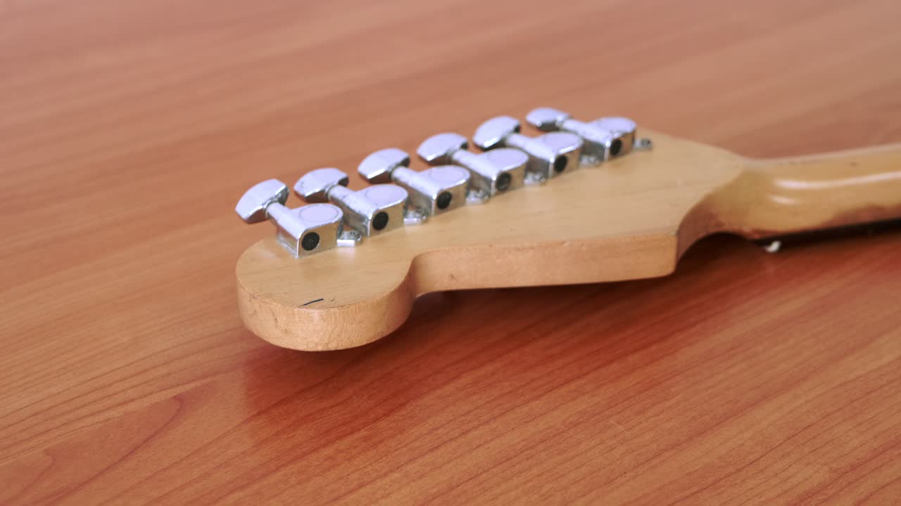deslice el movimiento de la vieja guitarra eléctrica con un patrón fino de cuerdas de guitarra colocadas sobre una mesa de madera
