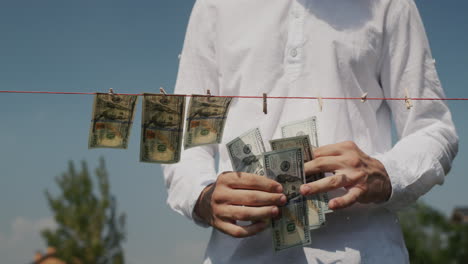 A-man-removes-banknotes-from-a-clothesline.-Corruption-and-money-laundering-concept