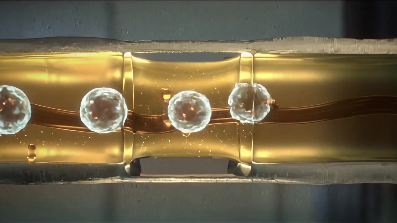 Gliding three bright bubbles along glass tube on lab bench, flow driving motion, filament visible