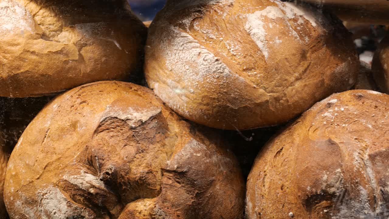 Lots of fresh delicious crusty tasty traditional big round loafs of bread with flour, pan right, bakery scene, nobody, bread loaves stacked. Baking industry, healthy food, freshness abstract concept