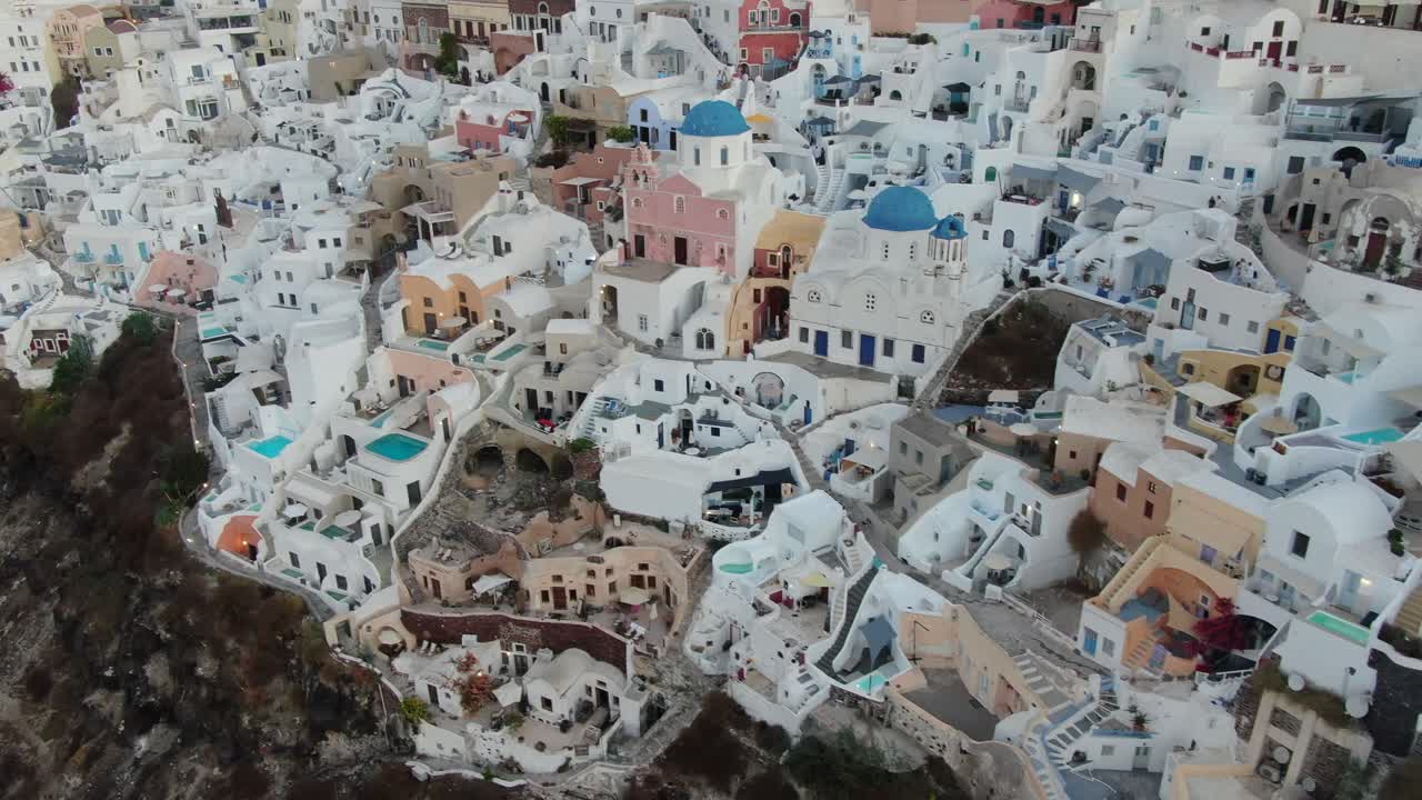 vista de avión no tripulado en grecia volando sobre santorini con la ciudad de oia casas blancas y techos azules en un acantilado junto al mar mediterráneo al amanecer