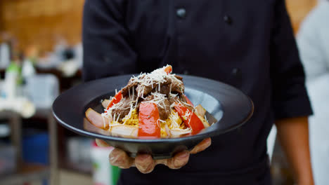 amazing slow motion and zoom in shot of the presentation of a peruvian dish called lomo saltado while a cook holds it in one hand