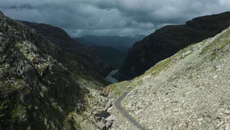 a narrow asphalt road snakes through the rocky norwegian roldalsfjellet valley