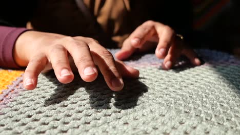 close-up of hands resting on a knitted blanket