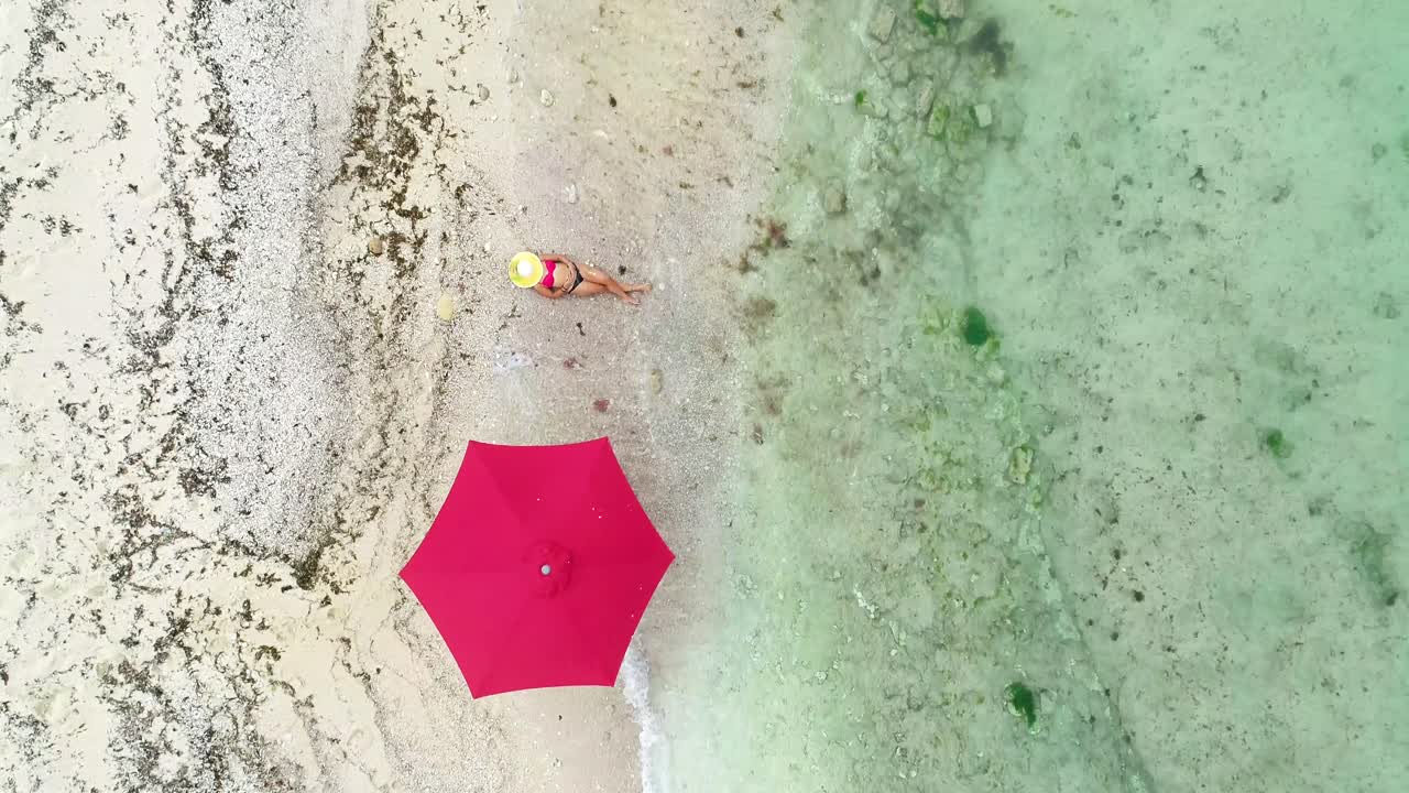 vista aérea superior de una mujer tomando el sol con una sombrilla en la orilla del mar, una plataforma rodante en