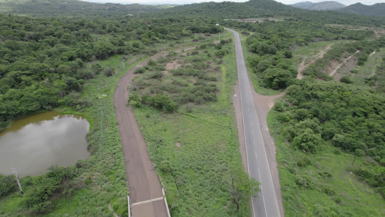 aerial view powerful metaphor of a paved road and a dirt path diverging through a serene, green landscape in rural Venezuela