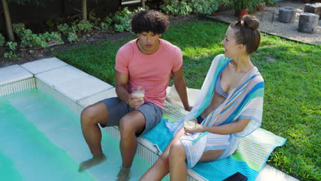 relaxing by pool, diverse couple enjoying drinks and conversation on sunny day, copy space