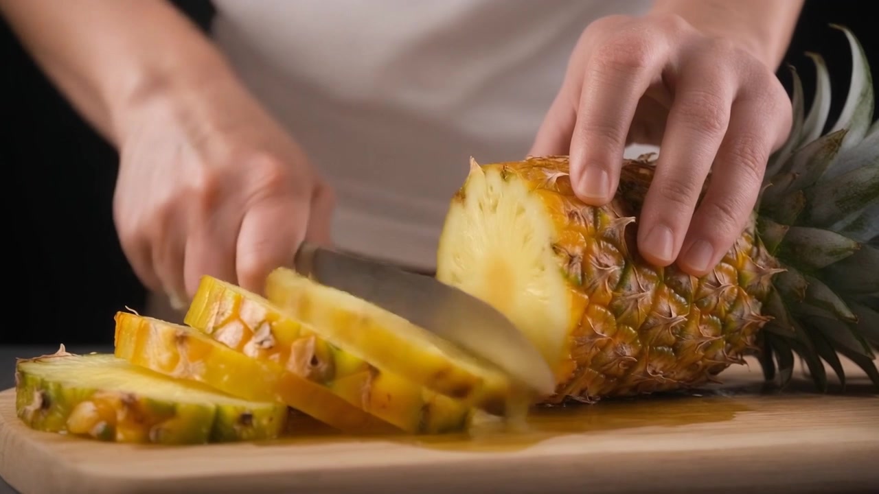 Person Slicing Fresh Pineapple on a Wooden Cutting Board
