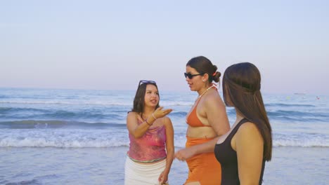 latin women walking together along the sandy shoreline, enjoying sunset conversation with ocean waves gently rolling nearby, embodying carefree friendship and summer vacation mood