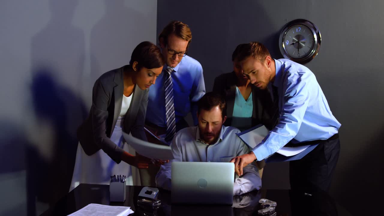 Businessman discussing over laptop and document with colleague in office