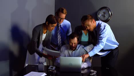 Businessman-discussing-over-laptop-and-document-with-colleague-in-office