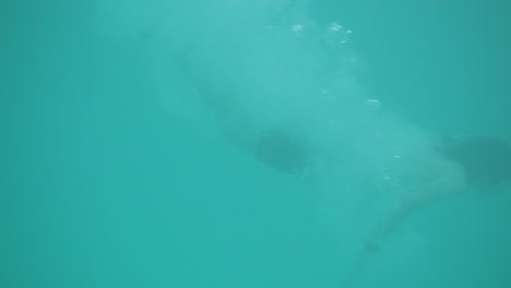 niño salta a la piscina y se sumerge en azul