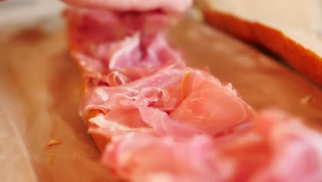 carefully arranging prosciutto on baguette