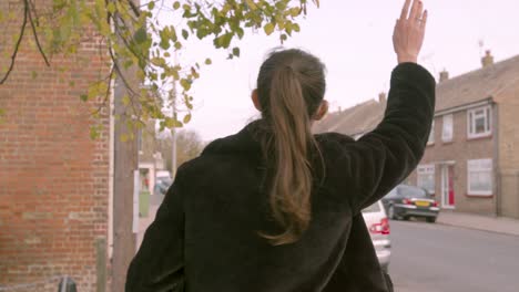 mujer con una máscara facial medial esperando en la calle y saludando a un autobús o taxi