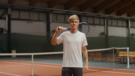 uomo che tiene una racchetta da tennis su un campo da tennis coperto