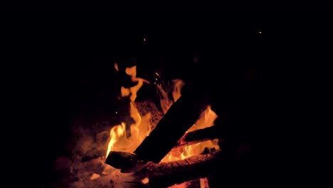 hot, glowing embers float into the night sky as a bonfire smokes and burns on the beach in the magdalen islands