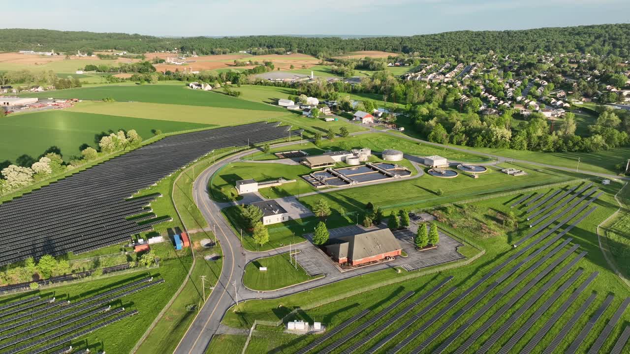 Large Solar Panels Farm during sunny day in America. Aerial wide shot. Sewage treatment plant in Ephrata, Pennsylvania. American neighborhood in distance.
