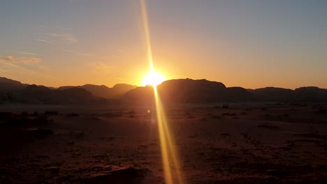 Final-rays-of-sunlight-behind-mountains-with-golden-sunset-overlooking-vast,-mountainous-Arabian-desert-landscape-in-Jordan,-Middle-East