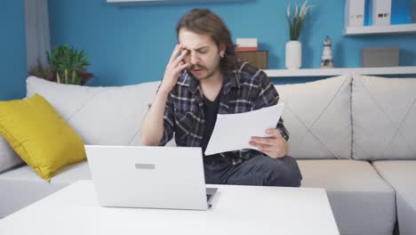 el trabajador de la oficina en casa mira el documento y se enoja.