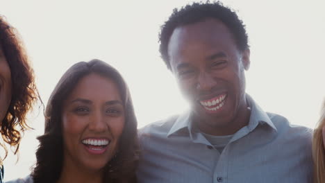 Portrait-Of-Group-Of-Multi-Cultural-Friends-Outdoors-Against-Flaring-Sun