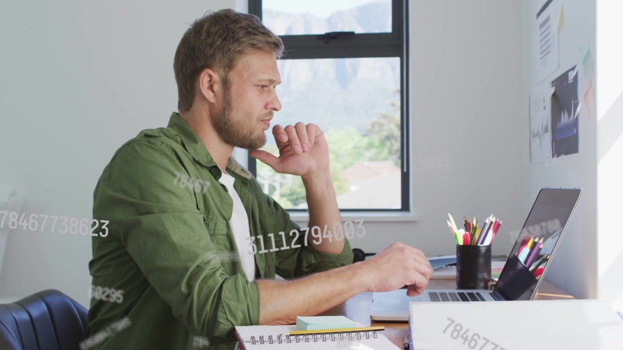 Mid-adult man typing laptop by window, generating numeric overlays while analyzing finance charts