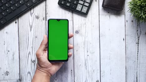 Top-view-of-man-hand-using-smart-phone-on-office-desk