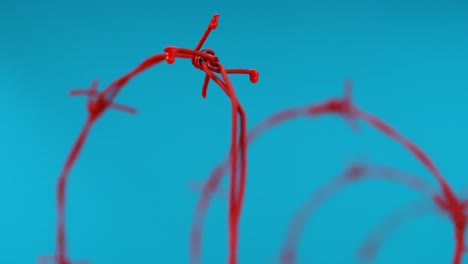 gotas rojas de líquido caen del alambre de púas contra un fondo azul, simbolizando la expresión artística