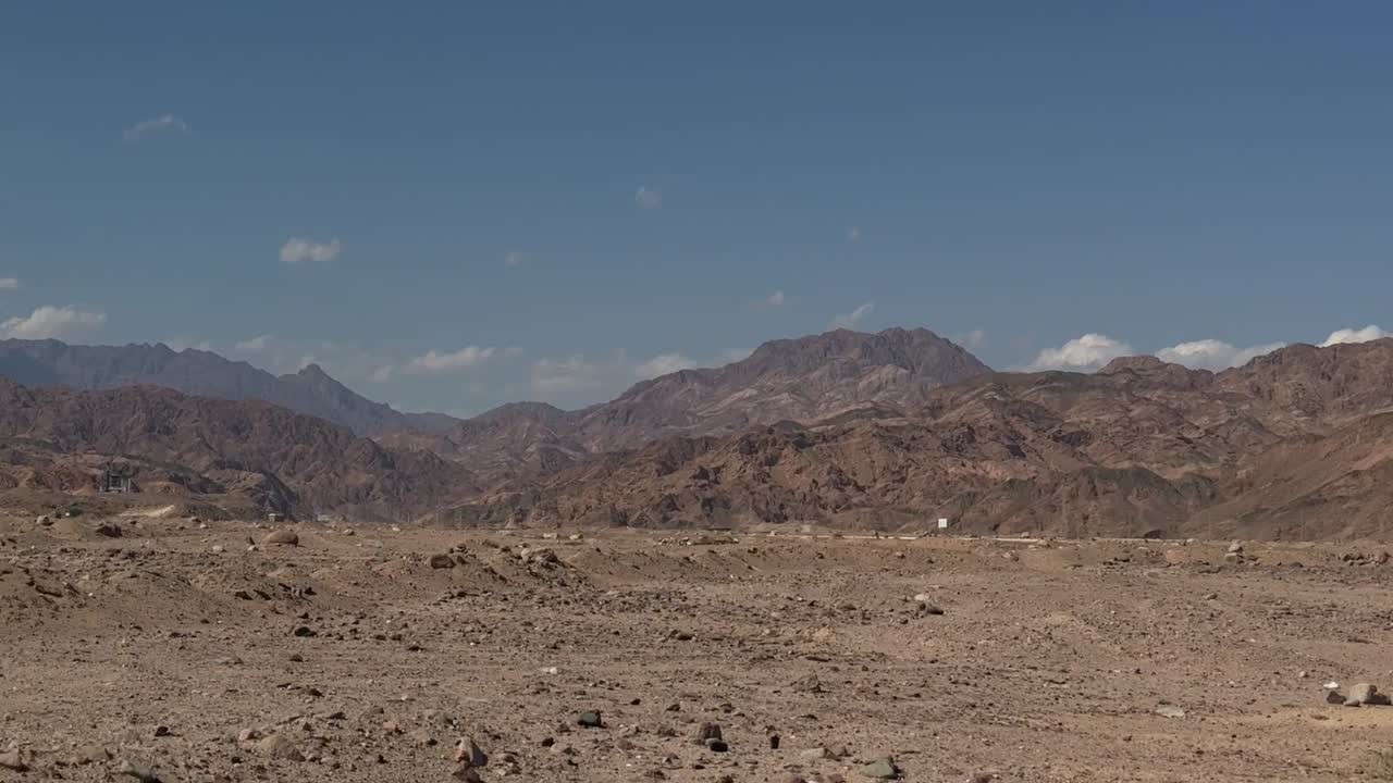 una vista de una montaña en el desierto desde un coche en una carretera, disparo de camiones